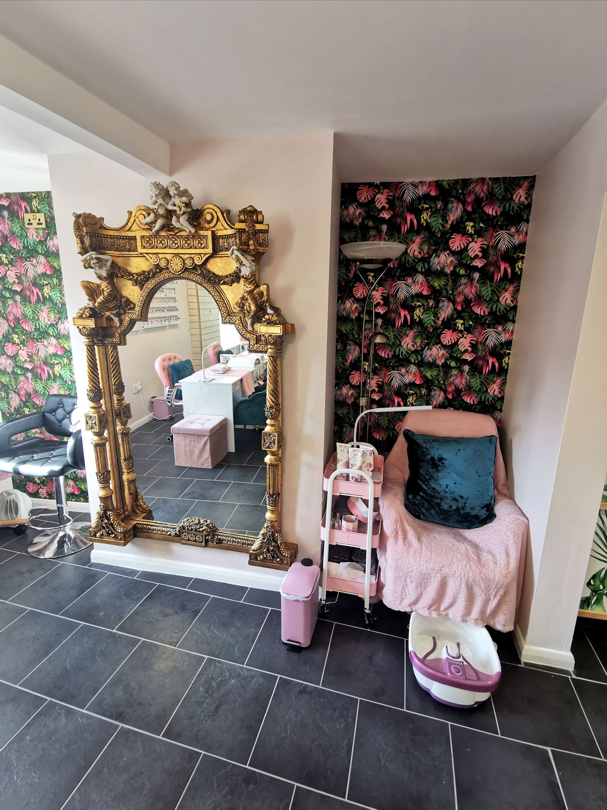 Ornate gold mirror beside a pink floral feature wall and a pedicure chair