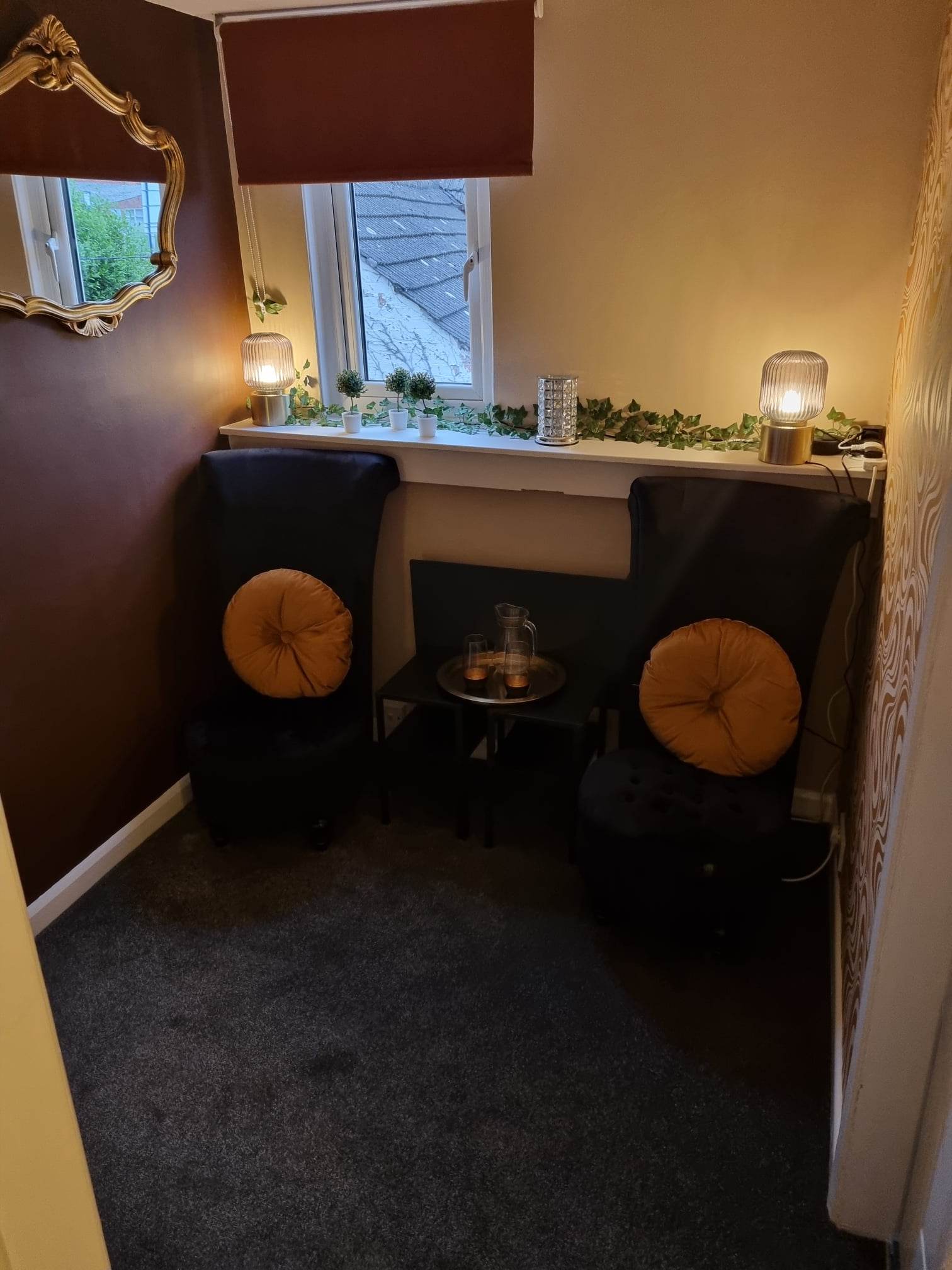 Cosy seating corner with mustard cushions, lamps and plants on the windowsill