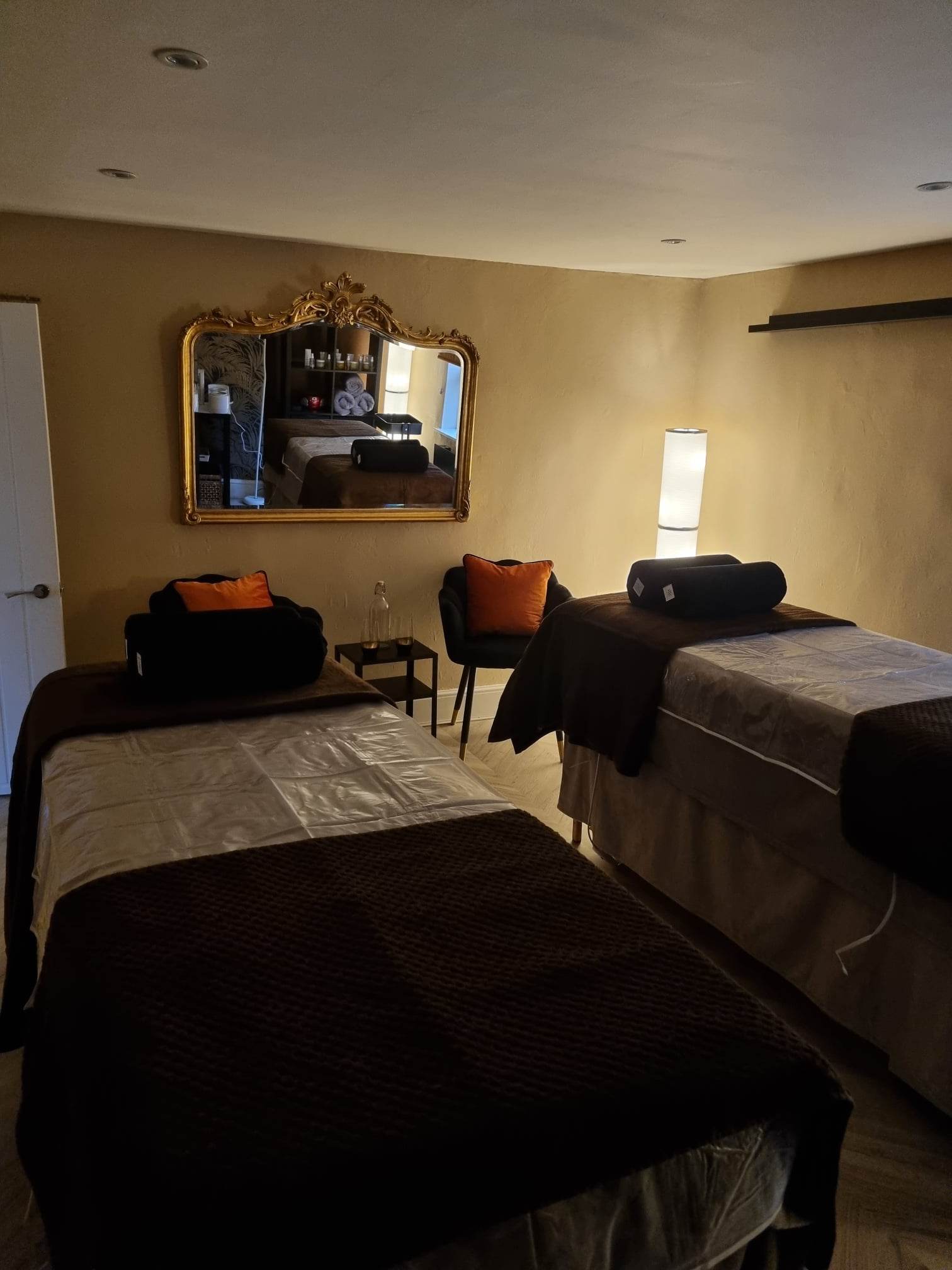 Two treatment couches side by side under a gold mirror